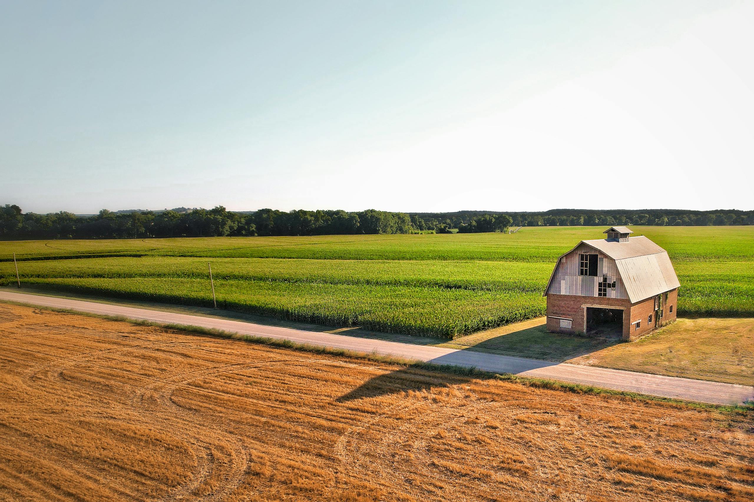 Aerial view of a historic barn and farmlands under a clear blue sky in Fredonia, Kansas.